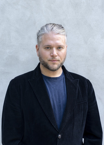 Author headshot of T. R. Miller in a dark jacket against a light background.